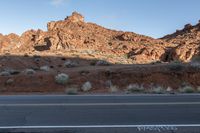 an empty street in a barren area in front of a mountain of rock with a sign indicating no traffic