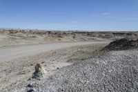 a dirt road is surrounded by some hills and desert like terrain as the vehicle sits on it