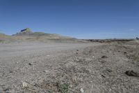 a dirt road is surrounded by some hills and desert like terrain as the vehicle sits on it