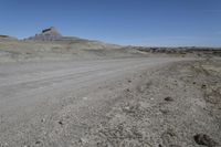 a dirt road is surrounded by some hills and desert like terrain as the vehicle sits on it