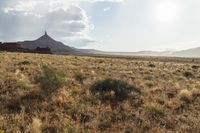 a very large desert plain with rocks and grass around it and the sun coming through