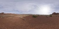 a large white cloud appears over a red ground with some rocks and bushes on it