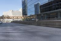 a bridge with cars parked at the side of it and buildings in the background and there is a blue car going on an elevated highway