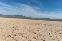 closeup shot of a dry landscape with mountains in the distance and a cloudy blue sky overhead