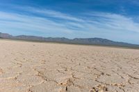 closeup shot of a dry landscape with mountains in the distance and a cloudy blue sky overhead