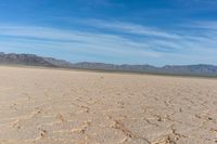 closeup shot of a dry landscape with mountains in the distance and a cloudy blue sky overhead