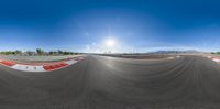 360 - view of an empty track in front of mountains and a bright blue sky