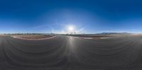 a panoramic image of an empty track under sun and sky lines in a desert area
