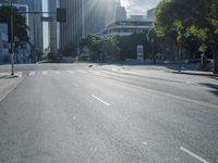 an empty street with buildings in the background and sun reflecting off the curb of a building