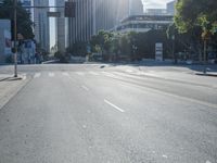 an empty street with buildings in the background and sun reflecting off the curb of a building