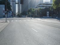 an empty street with buildings in the background and sun reflecting off the curb of a building