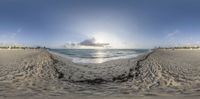 a wide fish eye view looking out towards a beach and the ocean at sunset,