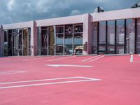 the building with white lines all over it in pink paint with a car parked in front
