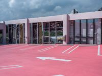 the building with white lines all over it in pink paint with a car parked in front