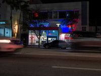 there is a street that is lit up with blue and pink lights at night time