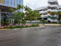 a very nice building in the middle of a tree covered street corner area with some buildings and shrubs growing around