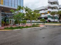 a very nice building in the middle of a tree covered street corner area with some buildings and shrubs growing around