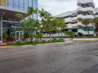 a very nice building in the middle of a tree covered street corner area with some buildings and shrubs growing around