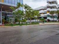 a very nice building in the middle of a tree covered street corner area with some buildings and shrubs growing around