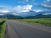 a lone country road is in the countryside area with mountains on both sides and barbed fence between the two sides