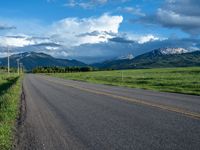 a lone country road is in the countryside area with mountains on both sides and barbed fence between the two sides