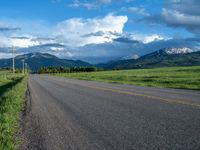 a lone country road is in the countryside area with mountains on both sides and barbed fence between the two sides