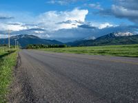 a lone country road is in the countryside area with mountains on both sides and barbed fence between the two sides