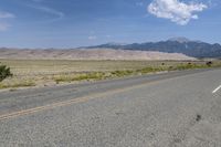 a lone motorcycle on a deserted open road with mountains in the background, at the bottom of the highway