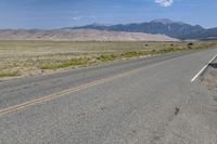 a lone motorcycle on a deserted open road with mountains in the background, at the bottom of the highway