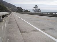 an ocean view from behind a guard rail on the side of a highway next to a cliff