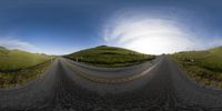 a fish eye lens image of the mountains and highway with hills in the background and an empty road going into the foreground