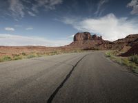 a empty highway with mountains in the background in the desert outside of the town of moab, utah