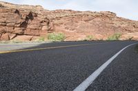 a person riding a motorcycle along a narrow road through rocks and sand cliffs a grassy area on both sides