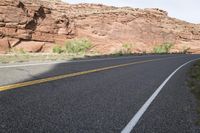 a person riding a motorcycle along a narrow road through rocks and sand cliffs a grassy area on both sides