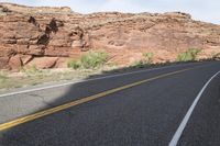 a person riding a motorcycle along a narrow road through rocks and sand cliffs a grassy area on both sides