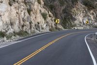 two yellow signs on the corner of a curve road in the mountains as if they were trying to cross one