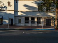 this is a white building with blue trim around the windows and a sidewalk in front