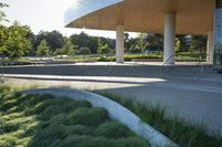 this is an open air terminal at a large building with tall columns, grass and stone steps