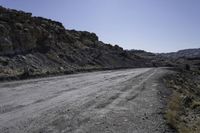 dirt road in the mountains surrounded by rock formations and shrubs, on a bright sunny day