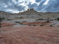 a person on a horse and in the wilderness with a red rock formation behind it