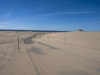 a paved beach with a fence in front of it and the ocean in the distance