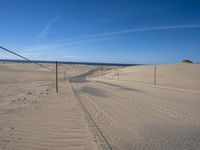 a paved beach with a fence in front of it and the ocean in the distance