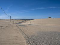 a paved beach with a fence in front of it and the ocean in the distance