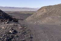 a car parked on a hill with rocks in the road side and a dirt road between two mountains