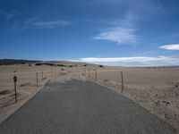 a paved beach with a fence in front of it and the ocean in the distance