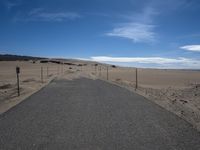 a paved beach with a fence in front of it and the ocean in the distance