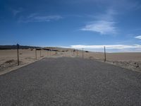 a paved beach with a fence in front of it and the ocean in the distance