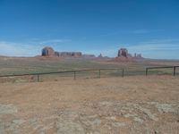 the view from a train traveling by the mountains of monument valley near a large gate that is open