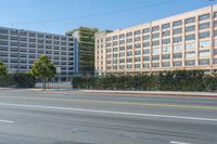 the view of the street with several tall buildings along it and a couple cars driving down it