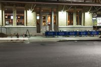 an empty city street at night with a sign showing parking places, and a building behind it